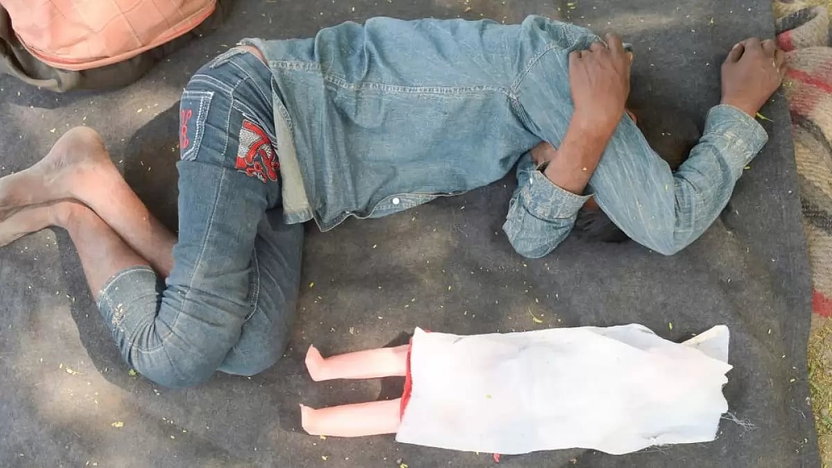 A man sleeps in the open with a covered doll by his side at Yamuna Ghat.