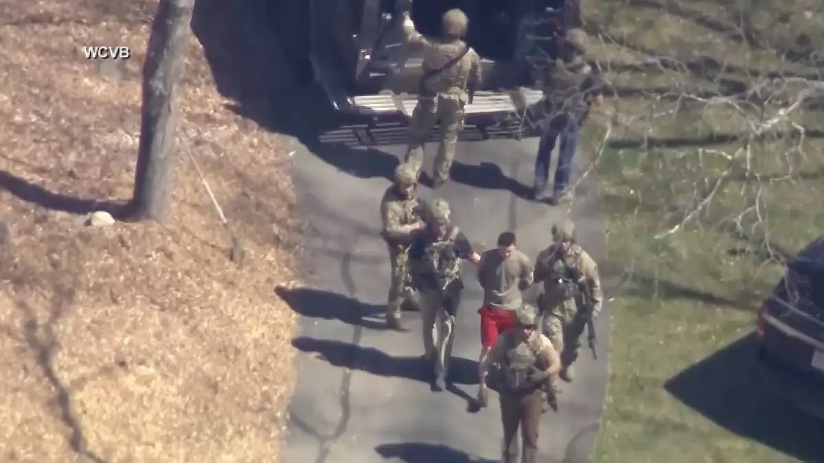 This image made from video provided by WCVB-TV, shows Jack Teixeira, in T-shirt and shorts, being taken into custody by armed tactical agents on Thursday, April 13, 2023, in Dighton, Mass. 