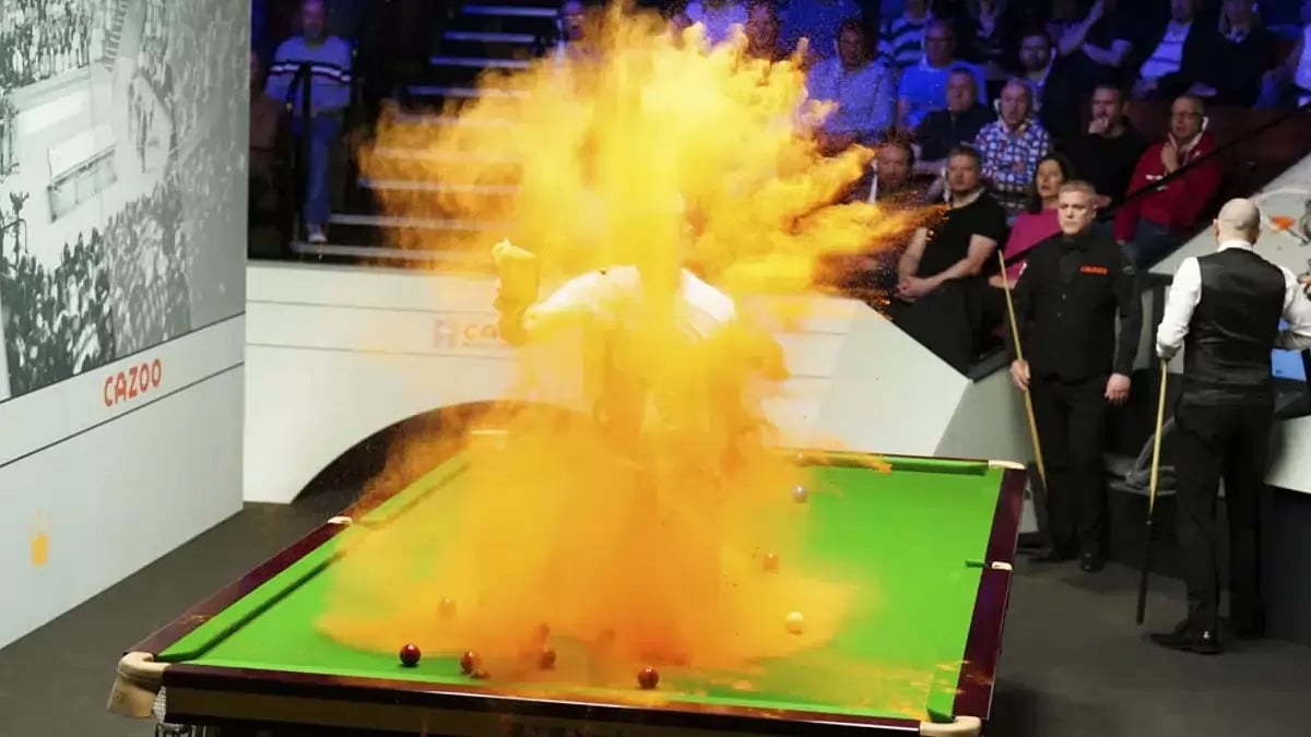 A 'Just Stop Oil' protester jumps on the table and throws orange powder during the match.