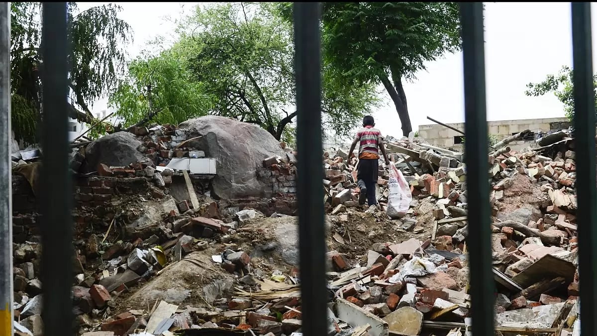A child rummages through the remains of his family home at Priyanka Gandhi camp in Vasant Vihar