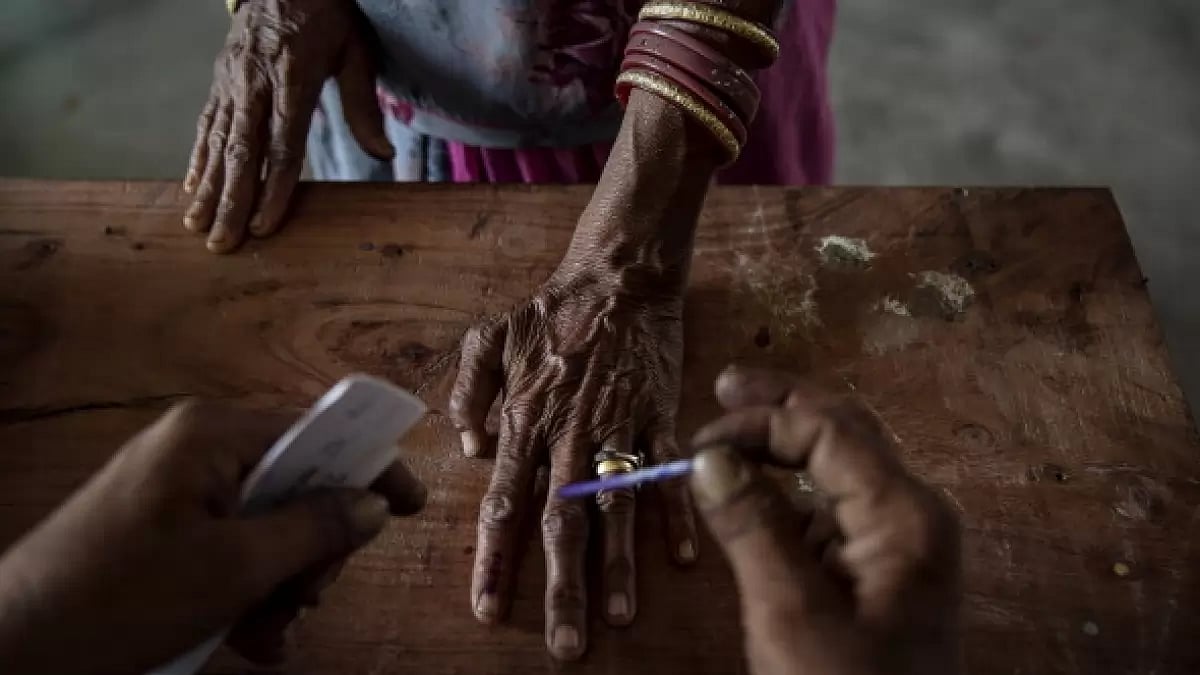 An Indian woman has her finger inked by an elections worker 