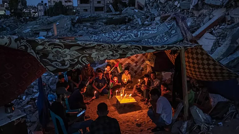 Palestinian children hold candles during a rally amid the ruins of houses destroyed by Israeli strikes in Gaza Strip. representational image - null