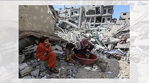 A Palestinian woman washes clothes among the rubbles of demolished houses