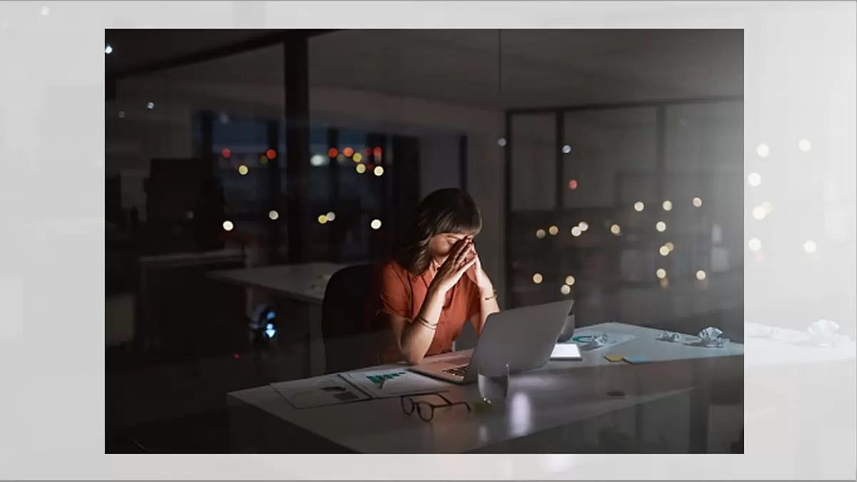A young woman covering her face on the desk in office