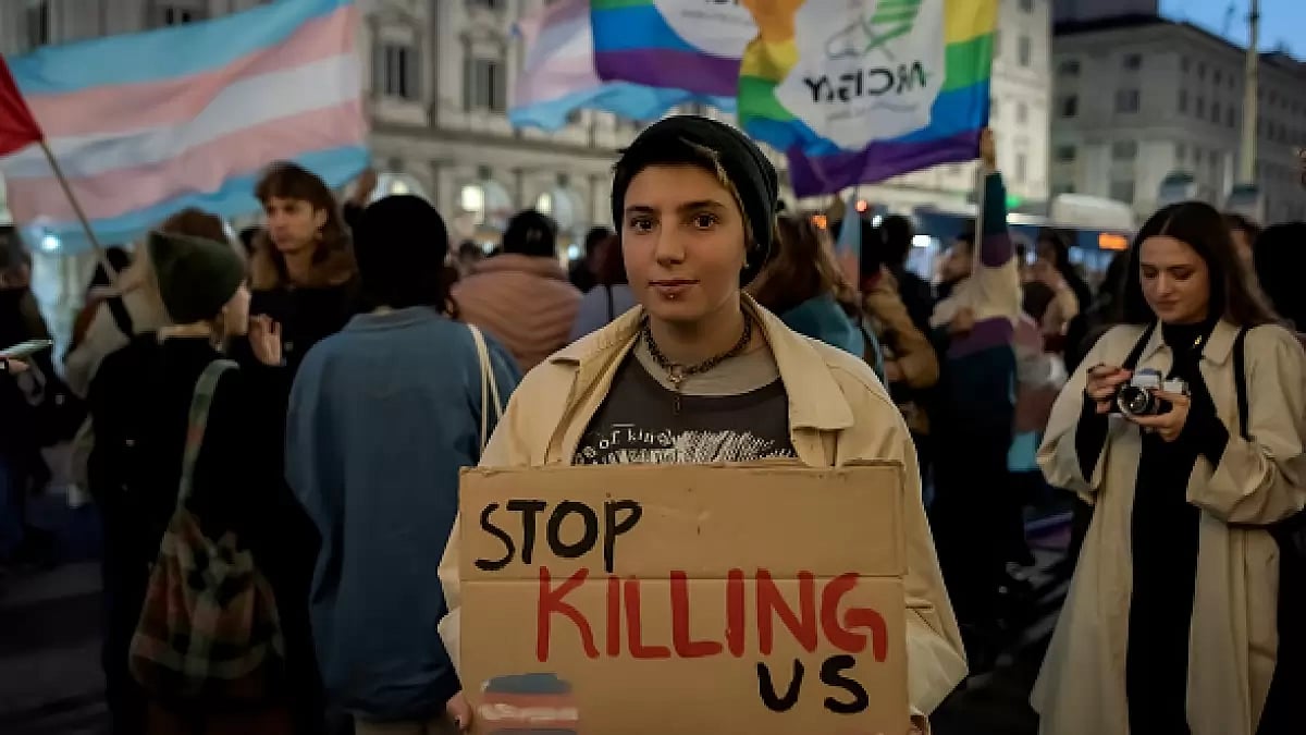 A trans-person holds a placard during a rally protesting violence against the community