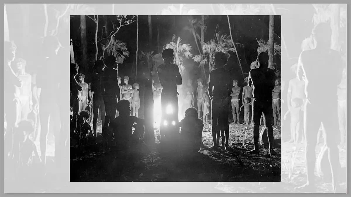 circa 1920: Australian aborigines gathered around a camp-fire during a carroboree, ceremonial dance.