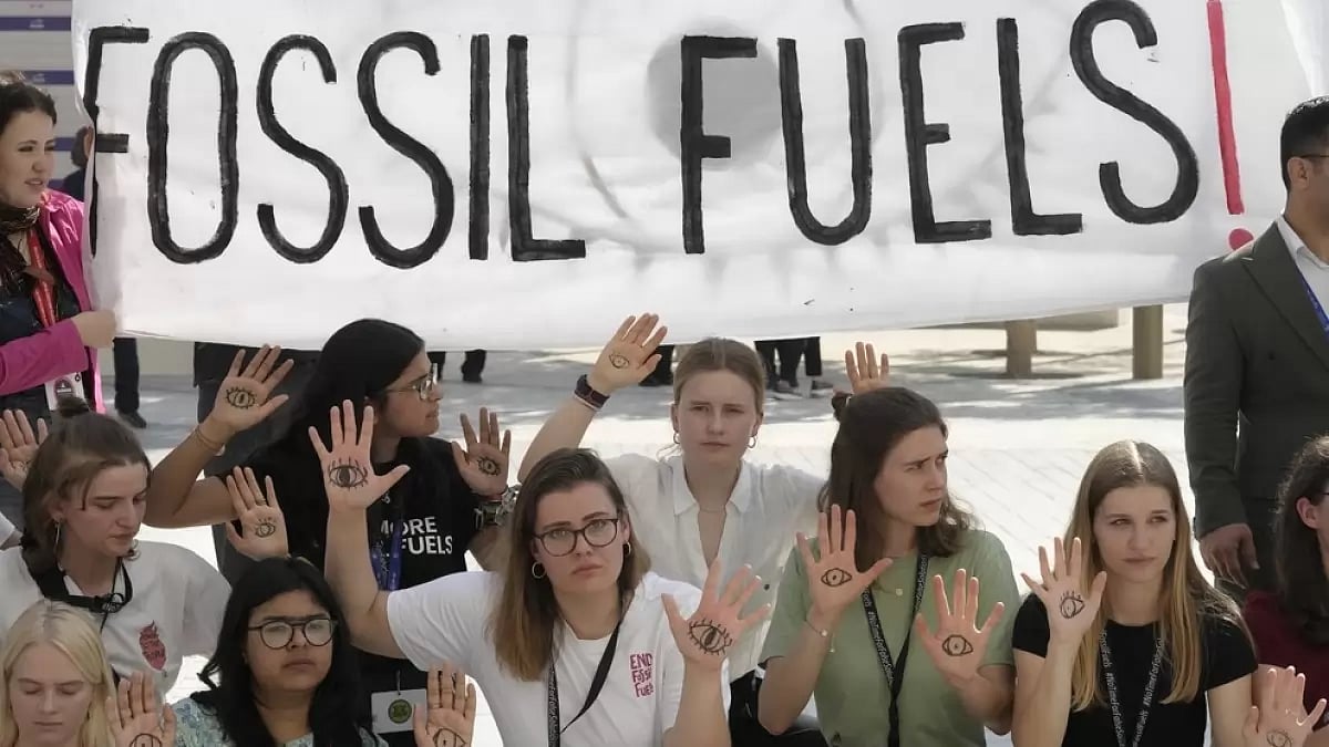 Activists demonstrate with a sign that reads fossil fuels at the COP28