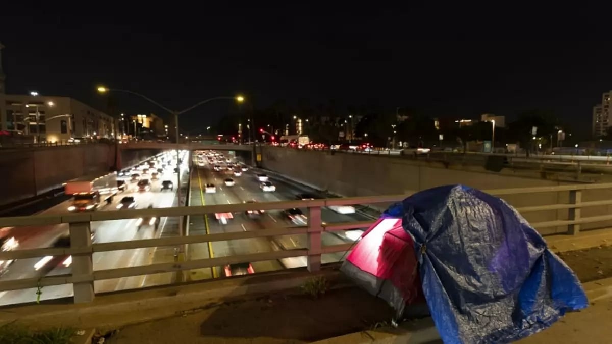 A tarp covers a portion of a homeless person’s tent on a bridge overlooking the 101 Freeway.