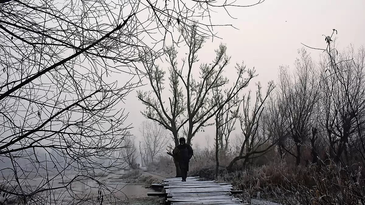Winter in the Valley: A man crosses a footbridge at the floating vegetable market of Dal Lake, Srinagar on a wintry morning