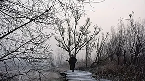 Winter in the Valley: A man crosses a footbridge at the floating vegetable market of Dal Lake, Srinagar on a wintry morning
