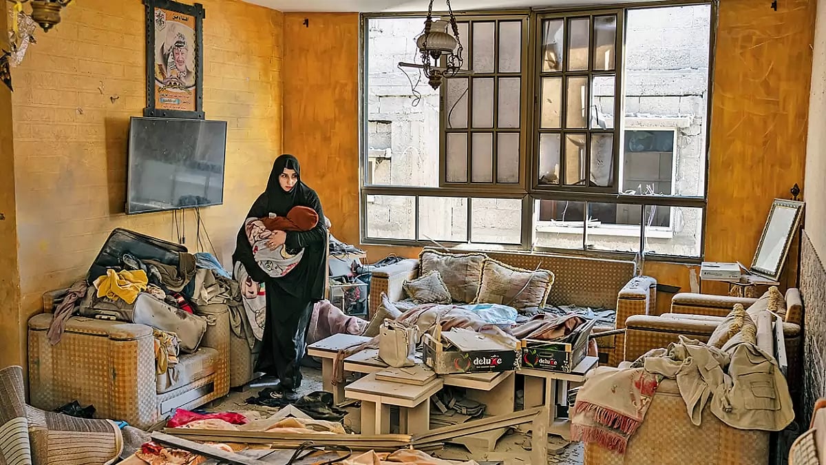 A Palestinian woman holds her child after an Israeli strike on her neighbourhood in Gaza Strip