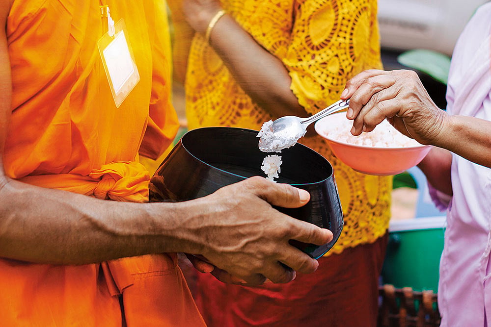 Shutterstock : Buddhist monks receiving alms during morning rounds