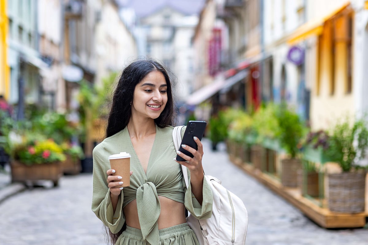 Shutterstock : A young traveller uses her smartphone on the go while exploring the city