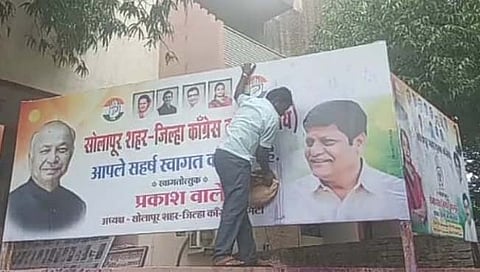 सोलापूर शहरातील काँग्रेस भवनाच्या बाहेरील बॅनरवर फेकण्‍यात आलेली शाई साफ करताना कर्मचारी.