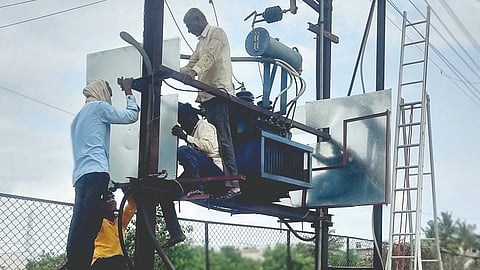 Power distribution company workers installing covers on transformers.