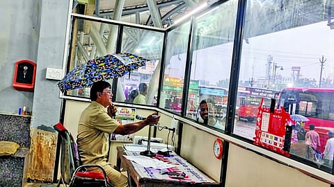 तुळजापूर बसस्थानकाच्या कंट्रोल रूममध्ये पावसापासून बचावासाठी छत्री घेऊन काम करताना नियंत्रक.