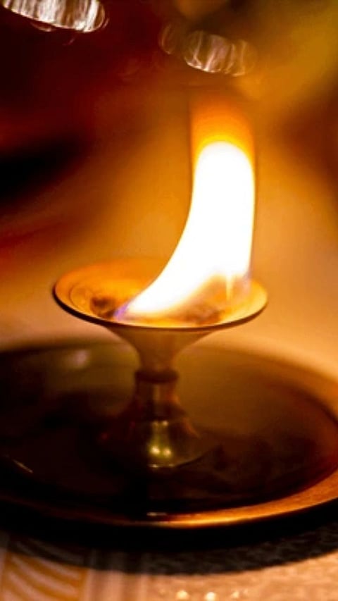 Burning camphor during a Hindu puja ritual on a traditional brass plate.