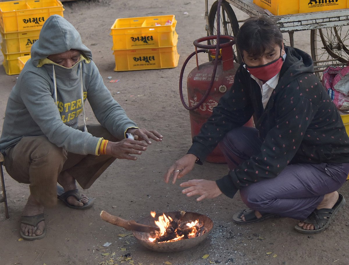 سردی میں آگ جلا کر خود کو گرم رکھنے کی کوشش میں دو افراد / تصویر یو این آئی