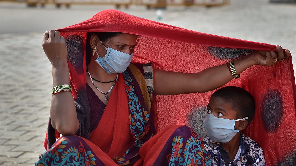 راجدھانی دہلی میں کورونا کے دور میں اپنے بچے پر سایہ کرتی ایک خاتون / Getty Images