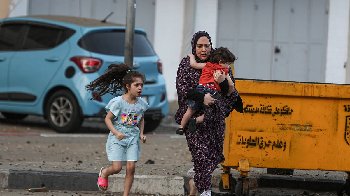 بدحواس حالت میں فلسطینی خاتون اپنے بچوں کی حفاظت کی کوشش کرتے ہوئے / Getty Images