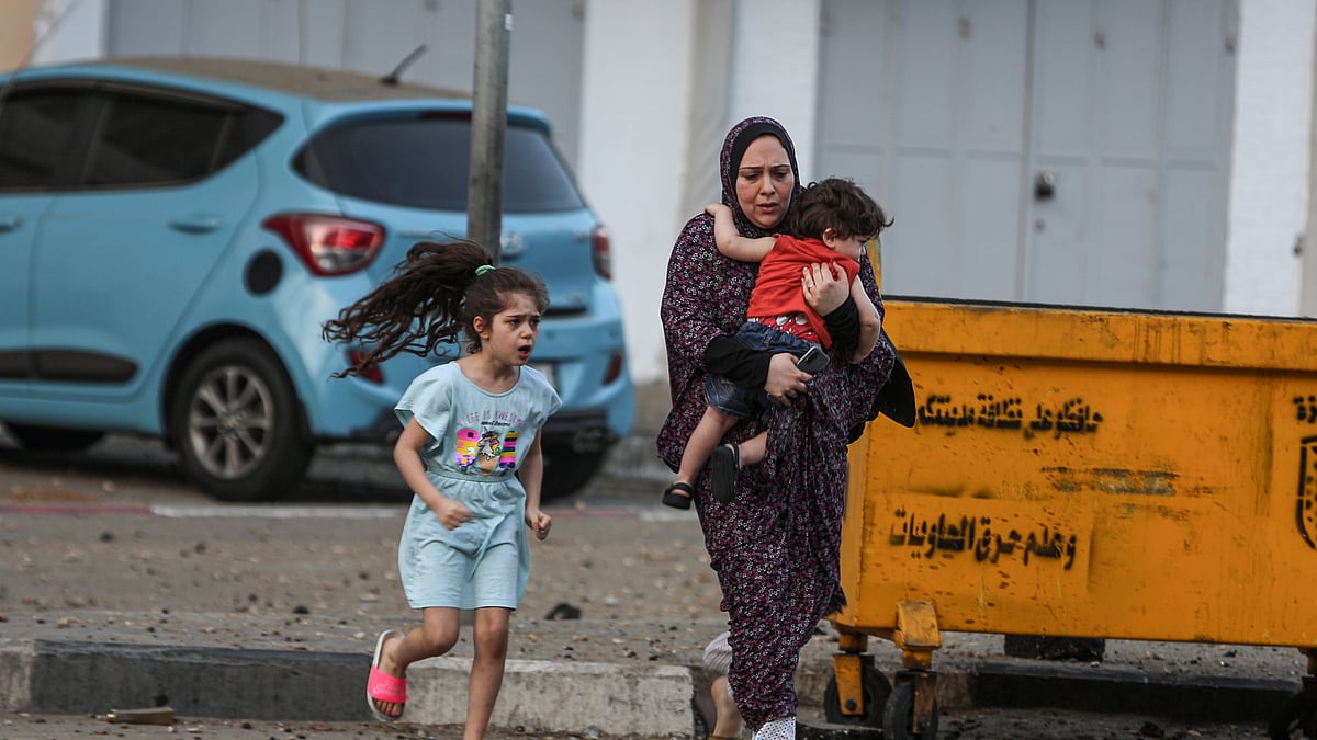 بدحواس حالت میں فلسطینی خاتون اپنے بچوں کی حفاظت کی کوشش کرتے ہوئے / Getty Images
