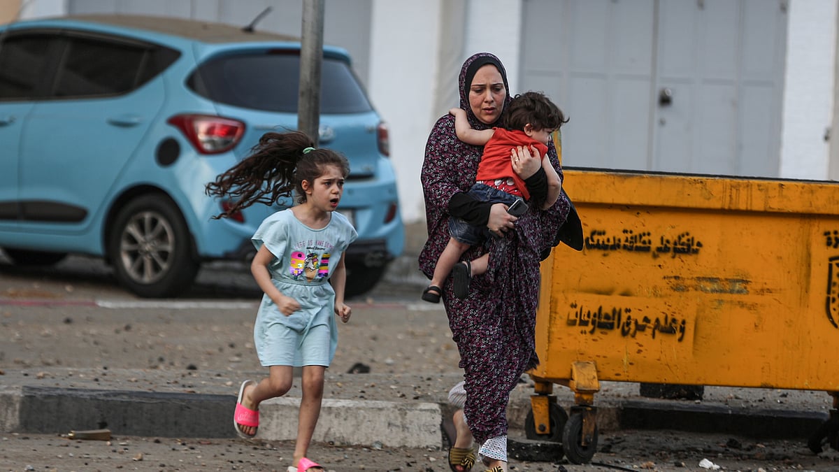 بدحواس حالت میں فلسطینی خاتون اپنے بچوں کی حفاظت کی کوشش کرتے ہوئے / Getty Images