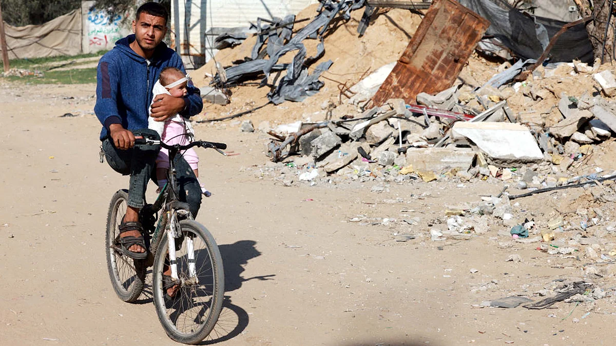 <div class="paragraphs"><p>بچے کے ساتھ ملبہ کے قریب سے گزرتا ہوا ایک فلسطینی نوجوان / Getty Images</p></div>