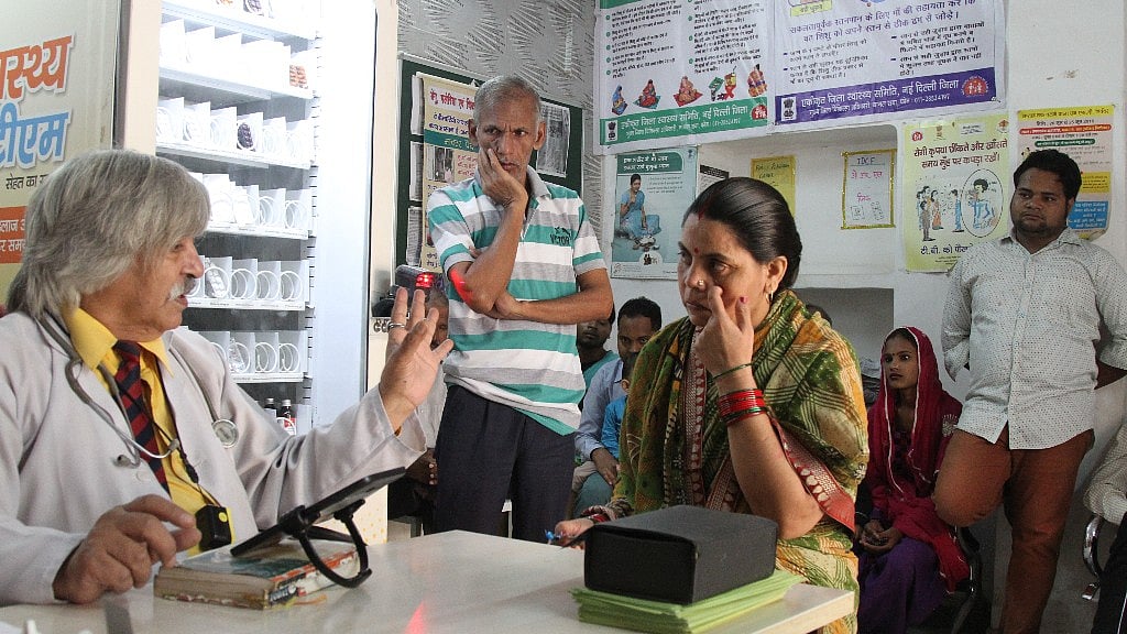  पश्चिमी दिल्ली में तोड़ापुर मोहल्ला क्लिनिक के डॉक्टर आर पाल मरीजों का इलाज करते हुए