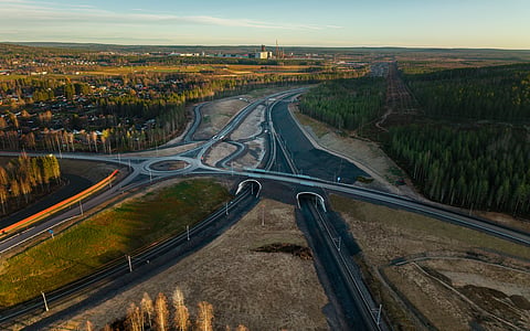 Det nya elektrifierade industrispåret, här sett från väster. Stegras blivande stålverk anas i bakgrunden vid den stora vita byggnaden med mörk skorsten. Spåret förbinder stålverket med järnvägen mellamn Kiruna och Luleå (nedanför bilden). Det nya industrispåret förgrenar sig i två spår för att tågen ska kunna åka ut på järnvägen åt båda håll.