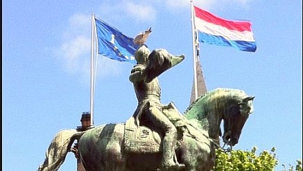 EU-flaggan vajar intill den nederländska, vid statyn av Nederländernas tidigare kung Vilhelm II i Haag. Nu implementerar Nederländerna EU:s mest strikta asylregler.