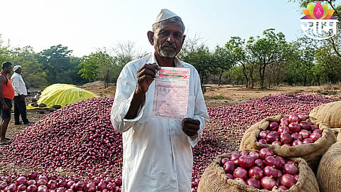 A distressed farmer looks at his onion produce after receiving extremely low market rates in Maharashtra.