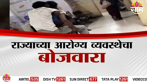 A distressed woman carries her stroke-affected husband on her back inside Akola District Hospital due to the unavailability of a stretcher, exposing severe lapses in the healthcare system.