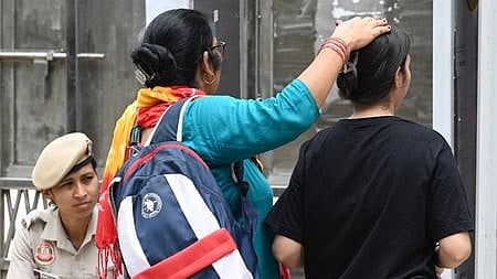 A NEET-UG aspirant seeks blessings from her guardian before entering an examination centre to appear for the NEET-UG 2026 re-examination, in New Delhi