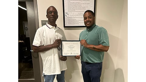 100 Families Initiative Client Frederick Young with his commercial driver’s license certification and 100 Families Initiative Client Advocate Kambrei Charles.
