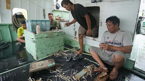 FOREIGN helpers do some maintenance work on their fishing tools while sitting on their boat docked at the Tomari fishery port in Naha in the main Okinawa island, southern Japan, on June 1, 2023.   