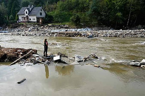 A woman stands by a river as residents return to clean up after recent floods near Pisecna, Czech Republic, Thursday, Sept. 19, 2024.