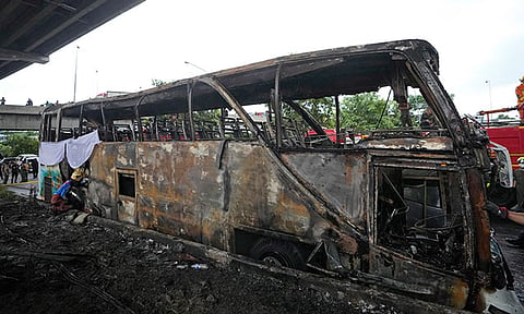 A rescuer inspects a bus that caught fire, carrying young students with their teachers, in suburban Bangkok, Tuesday, Oct. 1, 2024.