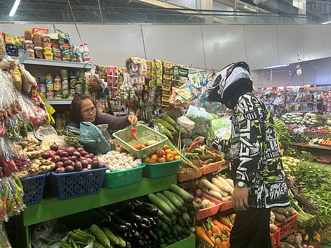 WEIGHING OPTIONS. Alyas “Bani” carefully picks vegetables from vendor Tina Ginga’s stall at the Agdao Public Market in Davao City on Monday as he stretches his budget amid rising vegetable prices. Bani said he now buys only enough ingredients for the week to keep his spending within limit
