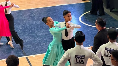 GOLDEN DANCE. Yanie Mae Chan and Eliju Joseph Darvin of F. Bustamante Central Elementary School in Davao City glide across the floor during the dancesport competition at the 2026 Palarong Pambansa. The duo dominated the standard division, collecting six gold medals in Modern Standard Grade A, tango, foxtrot, quickstep, Viennese waltz, and slow waltz to complete a remarkable sweep for Davao Region.