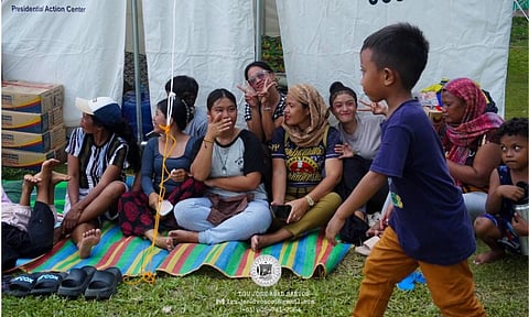 TEMPORARY REFUGE. Displaced residents take shelter inside a government relief tent in Lou Jose Abad Santos, Davao Occidental. Families gather on woven mats alongside stacked emergency food packs following recent environmental disruptions in the region.