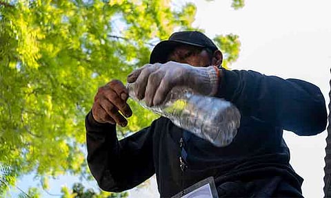 Elmer removes the cap and label from a PET bottle as part of proper waste segregation, applying his training on which materials can be recovered and have value.