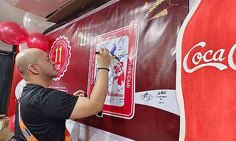 A member signs a commemorative map of the Philippines during the 11th-anniversary celebration of the Coca-Cola Collectors Club Philippines (2015–2026). The event, led by organization President Edward S. Secerio, gathered memorabilia enthusiasts and collectors from across the region to celebrate over a decade of community and shared passion.