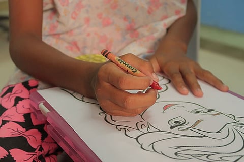 A six-year-old girl Mica coloring a cartoon at the Kean Gabriel Foundation.