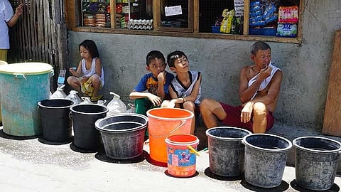 CEBU. In this file photo, members of a family in Barangay Pardo, Cebu City spend the whole morning on the roadside waiting for the fire truck that will bring them water.