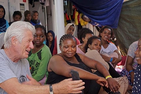 MEDITERRANEAN. Actor Richard Gere, left, talks with migrants aboard the Open Arms Spanish humanitarian boat as it cruises in the Mediterranean Sea, Friday, Aug. 9, 2019. Open Arms has been carrying 121 migrants for a week in the central Mediterranean awaiting a safe port to dock, after it was denied entry by Italy and Malta. (AP)