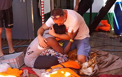 LAMPEDUSA, SOUTHERN ITALY. A migrant is comforted by a crew member of the Open Arms Spanish humanitarian boat off the coast of the Sicilian island of Lampedusa, southern Italy, Sunday, August 18, 2019. An Open Arms spokeswoman tells The Associated Press that the humanitarian group is not willing to sail to Spain's southernmost Algeciras port given the emergency situation that they are experiencing inside the boat. (AP)