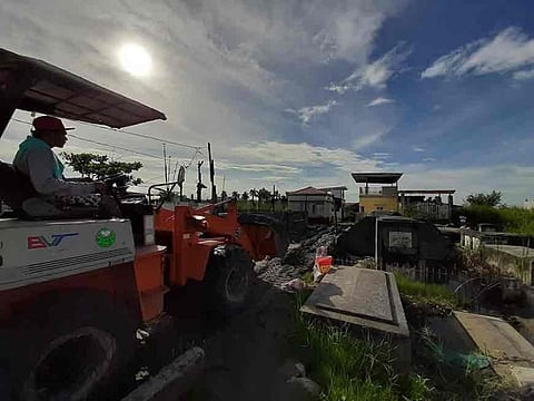 PAMPANGA. A man operates a small backhoe to upgrade the access way in a flooded cemetery in Masantol, Pampanga two days before All Saints' Day. (Princess Clea Arcellaz)