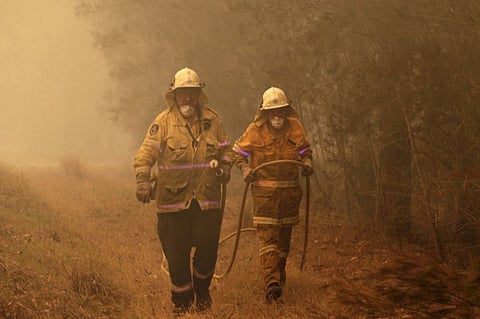 AUSTRALIA. Firefighters drag their water hose after putting out a spot fire near Moruya, Australia, Saturday, January 4, 2020. Australia's Prime Minister Scott Morrison called up about 3,000 reservists as the threat of wildfires escalated Saturday in at least three states with two more deaths, and strong winds and high temperatures were forecast to bring flames to populated areas including the suburbs of Sydney. (AP)  