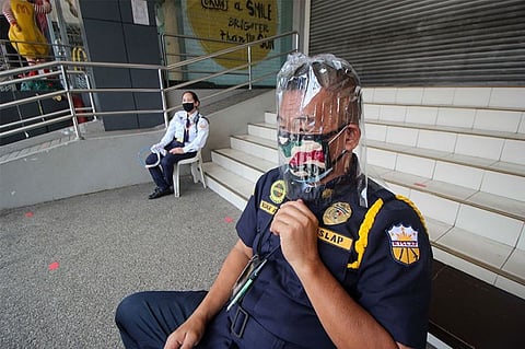 BENGUET. A security guard of a mall in La Trinidad uses DIY face protector made from magnetic plastic cover which is more comfortable than the company provided protective gear. (Photo by Jean Nicole Cortes)