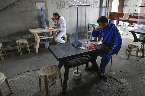 MANILA. Workers wearing protective suits eat at a restaurant with plastic sheet barriers to curb the spread of Covid-19 in Quezon City on Wednesday, Aug. 19, 2020. (AP)